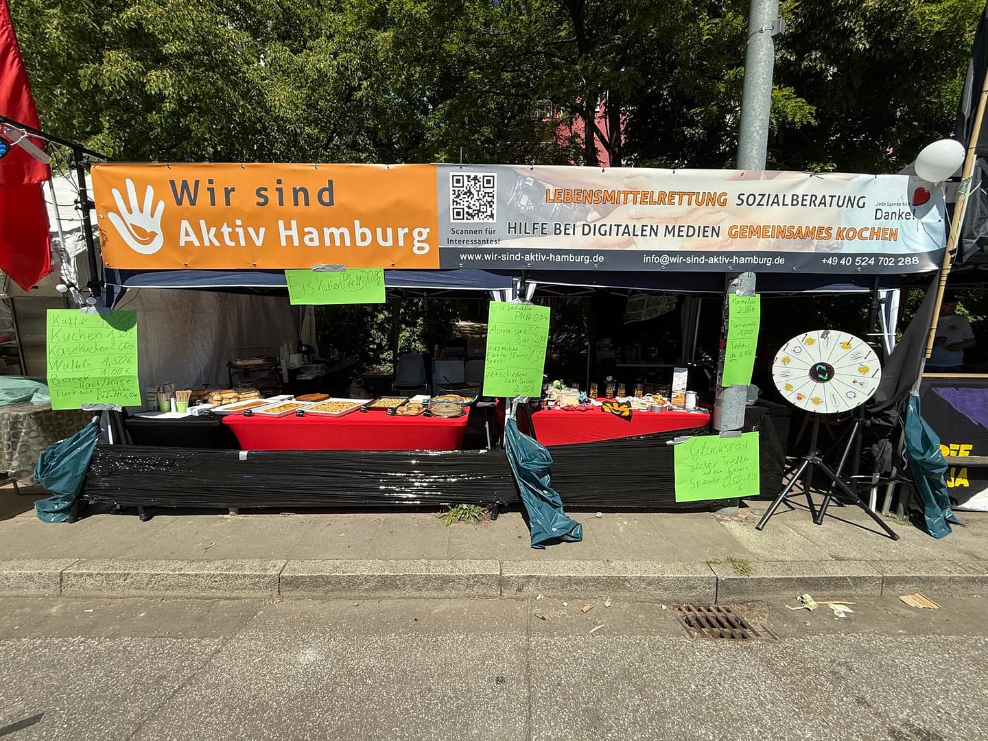 Infostand von Wir sind aktiv Hamburg beim alternativen Hafengeburtstag 2025 mit Kuchen, Kaffee und Glücksrad